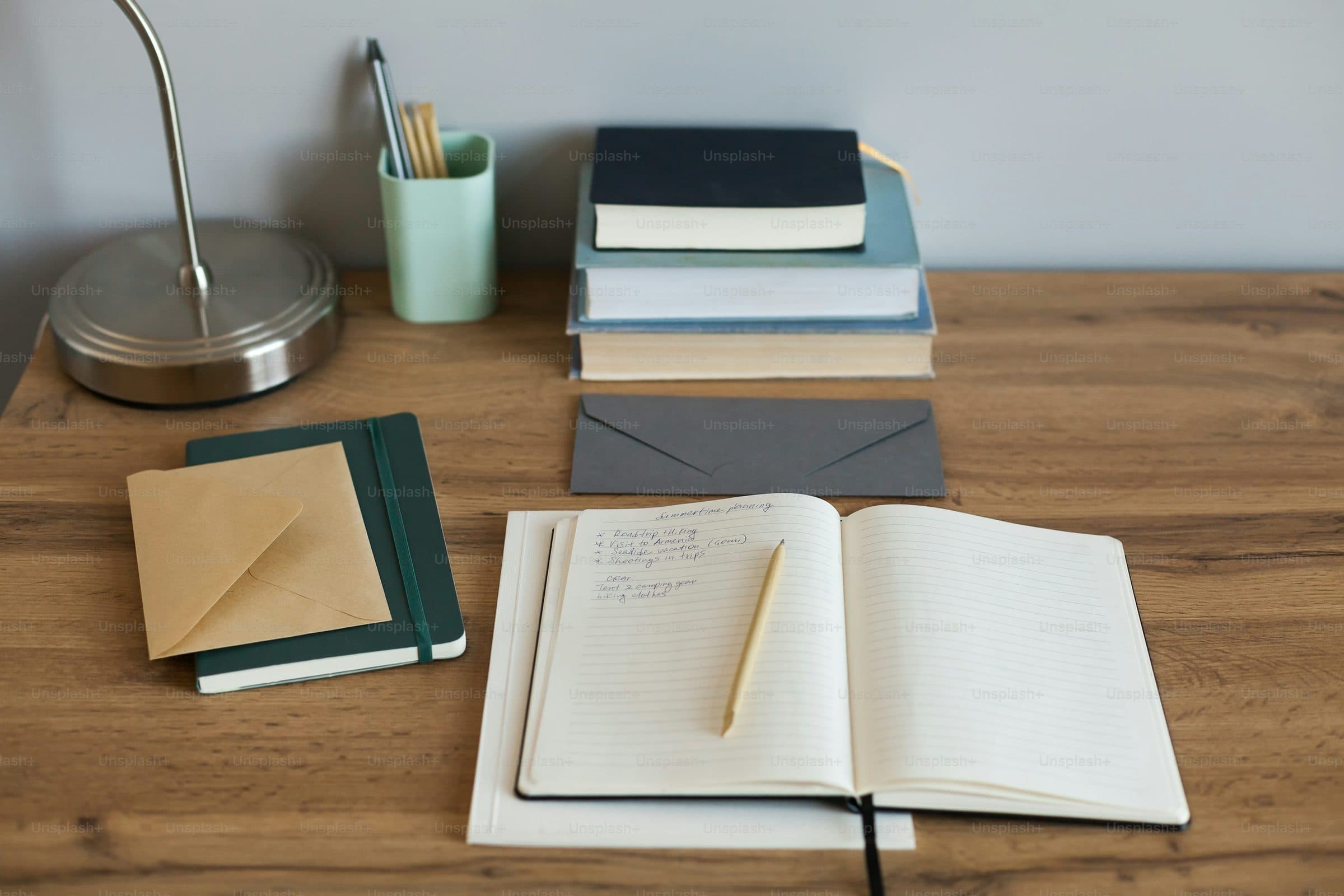 A desk with books, a notebook and a pen